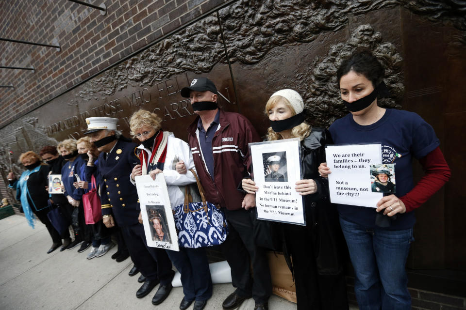 Family members of victims of the Sept. 11, 2001 attacks wear black gags over their mouths in protest of the transfer of unidentified remains of those killed at the World Trade Center from the Office of the Chief Medical Examiner to the World Trade Center site, Saturday, May 10, 2014, in New York. The remains will be transferred to an underground repository in the same building as the National September 11 Memorial Museum. (AP Photo/Jason DeCrow)