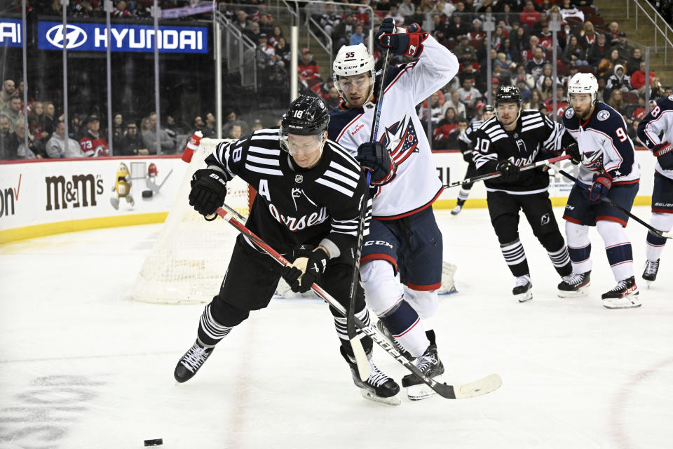 New Jersey Devils left wing Ondrej Palat (18) and Columbus Blue Jackets' David Jiricek (55) chase the puck during the second period of an NHL hockey game Friday, Nov. 24, 2023, in Newark, N.J. (AP Photo/Bill Kostroun)