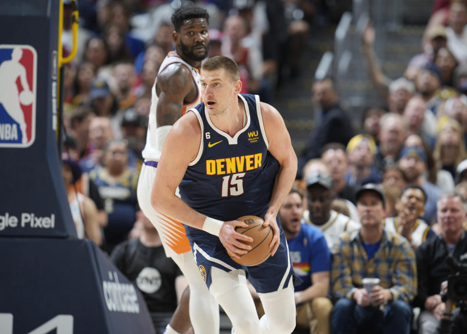 Denver Nuggets center Nikola Jokic (15) looks to pass the ball after pulling in a rebound in front of Phoenix Suns center Deandre Ayton, top, in the first half of Game 2 of an NBA second-round playoff series Monday, May 1, 2023, in Denver. (AP Photo/David Zalubowski)