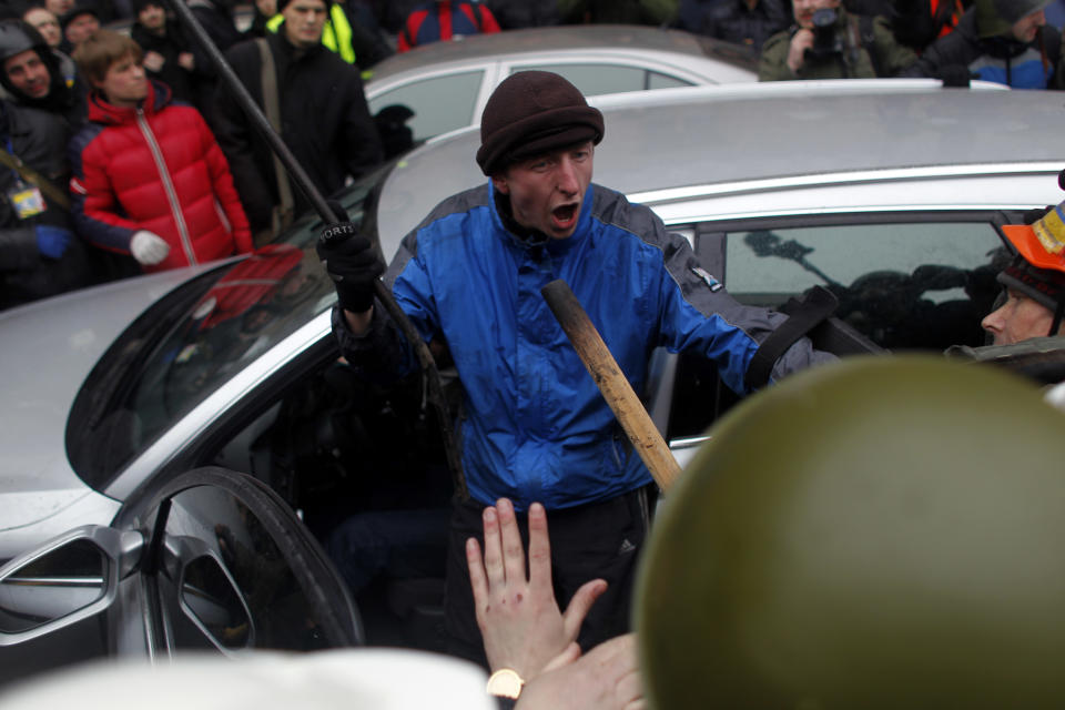 An anti-government protester tries to protect suspected supporters of Ukraine's embattled president Viktor Yanukovych from getting assaulted in Kiev, Ukraine, Saturday, Feb. 22, 2014. Fears that Ukraine could split in two mounted Saturday as regional lawmakers in the pro-Russian east questioned the authority of the national parliament. Protesters took control of Ukraine's capital and parliament sought to oust the president. (AP Photo/ Marko Drobnjakovic)