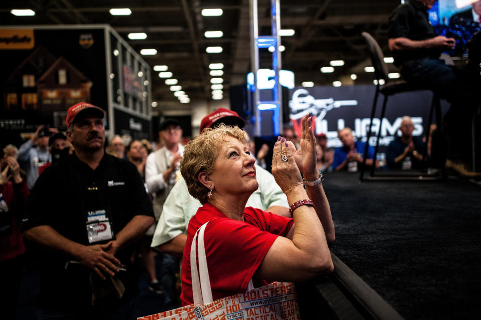 A woman claps in response to a speech by Trump as she watches a live feed of the event on the expo floor Friday.