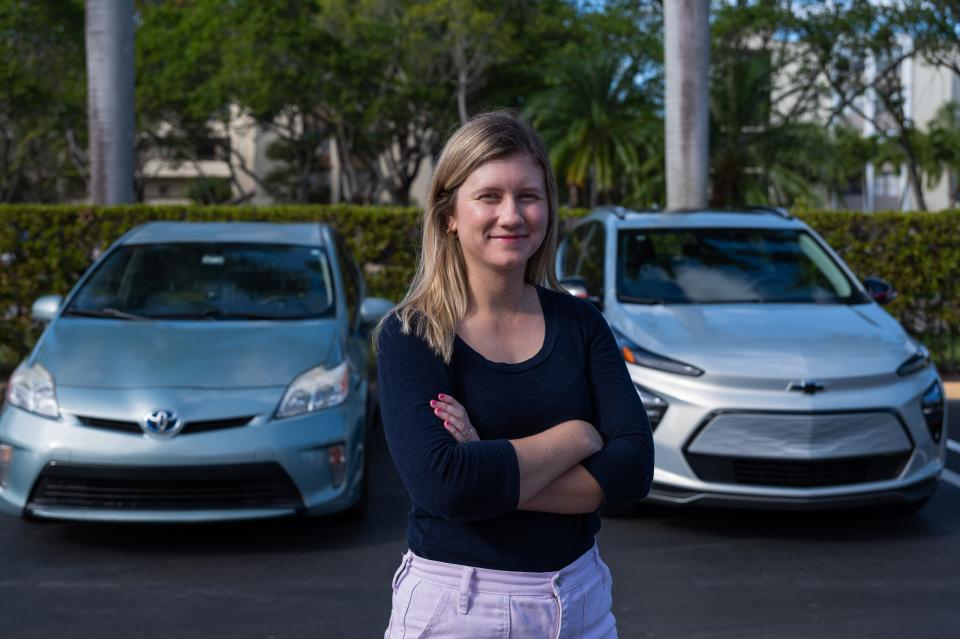 Palm Beach Post reporter Hannah Morse poses for a portrait standing in front of her personal vehicle, a Toyota Prius hybrid car, left, and a Chevrolet Bolt EUV, which she test drove for a week, seen on Tuesday, February 7, 2023, in Delray Beach, FL.