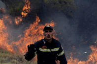 A firefighter reacts as flames rise during a wildfire near the village of Kapandriti, north of Athens, Greece, August 15, 2017. REUTERS/Alkis Konstantinidis