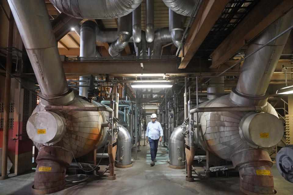 Intermountain Power Agency spokesperson John Ward walks through a coal power plant on Wednesday, June 22, 2022, in Delta, Utah. Developers in rural Utah who want to create big underground caverns to store hydrogen fuel won a $504 million loan guarantee this spring. They plan to convert the site of the 40-year-old coal plant to cleanly-made hydrogen by 2045. (AP Photo/Rick Bowmer)