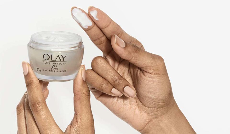 Open jar of Olay Total Effects 7 in 1 night cream in a woman&#39;s hands.