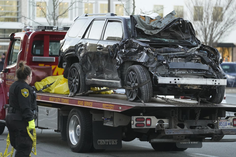The damaged SUV that crashed into an Apple store is removed from the site of the crash on a flatbed tow truck, Monday, Nov. 21, 2022, in Hingham, Mass. One person was killed and multiple others were injured Monday when the SUV crashed into the store, authorities said. (AP Photo/Steven Senne)