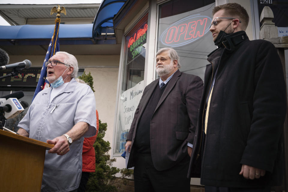 Karl Manke, 77, left, speaks during a press conference alongside his attorney David A. Kallman on Monday, May 11, 2020 at Karl Manke's Beauty & Barber Shop in Owosso, Mich. Manke has defied the governor's order not to conduct business. (Sarahbeth Maney/The Flint Journal via AP)