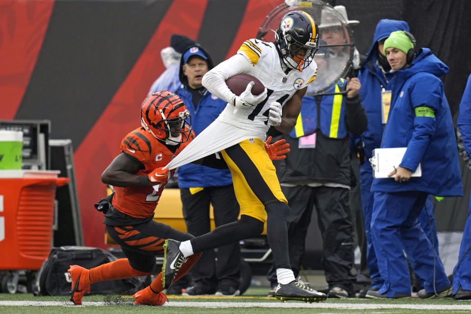 Pittsburgh Steelers wide receiver George Pickens (14) is tackled by Cincinnati Bengals cornerback Mike Hilton (21) after a 43-yard pass play during the second half of an NFL football game in Cincinnati, Sunday, Nov. 26, 2023. (AP Photo/Carolyn Kaster)