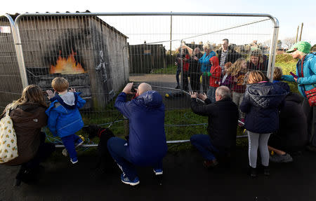 FILE PHOTO: People view new work by the artist Banksy that appeared during the week on the walls of a garage in Port Talbot, Britain December 22, 2018. REUTERS/Rebecca Naden/File Photo