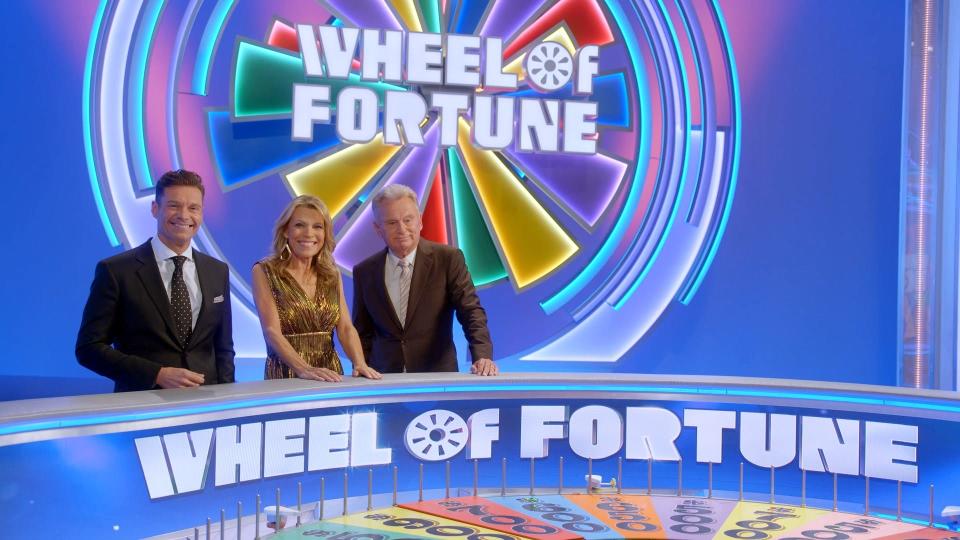 (L-R) New host Ryan Seacrest is welcomed on the set of "Wheel of Fortune" by co-host Vanna White and Pat Sajak, who has stepped down as host after 41 seasons.