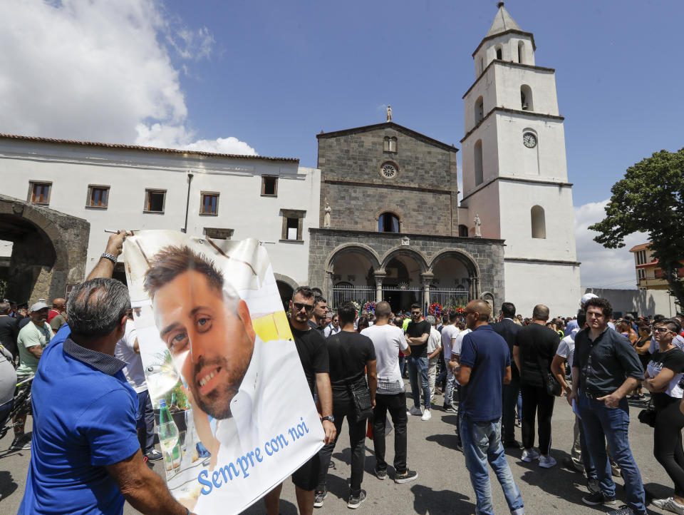 People unfold a banner reading in Italian: "Forever with us", and bearing a photograph of Carabinieri's officer Mario Cerciello Rega during his funeral in his hometown of Somma Vesuviana, near Naples, southern Italy, Monday, July 29, 2019. Two American teenagers were jailed in Rome on Saturday as authorities investigate their alleged roles in the fatal stabbing of the Italian police officer on a street near their hotel. (AP Photo/Andrew Medichini)