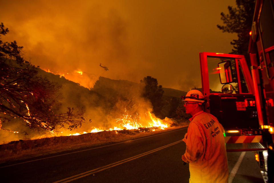 A firefighter watches as a helicopter drops water on the Lake Hughes fire in Angeles National Forest on Wednesday, Aug. 12, 2020, north of Santa Clarita, Calif. (AP Photo/Ringo H.W. Chiu)