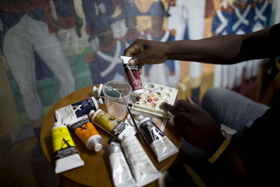 In this June 28, 2019 photo, Haitian artist Marc Gerard Estime works works on the restoration of a painting Haitian artist Edouard Duval Carrie, that was damaged during the earthquake 2010 at the Musée d'Art du Collège Saint Pierre, in Port-au-Prince, Haiti. The painting "The Republican Army of Santo Domingo," that was stripped down to blank canvas in certain areas. (AP Photo/Dieu Nalio Chery)