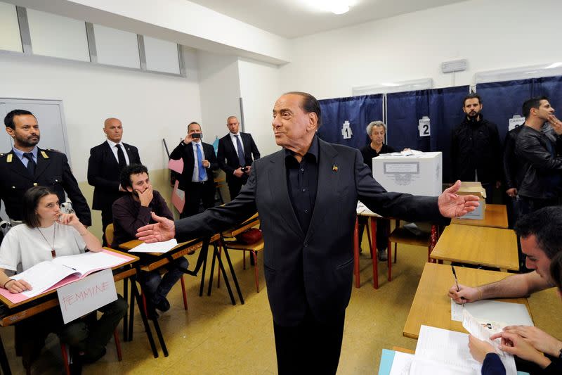 FOTO DE ARCHIVO. El personal de un colegio electoral mira mientras Silvio Berlusconi, ex primer ministro italiano y líder del partido Forza Italia, gesticula cerca de las mesas de inscripción durante las elecciones al Parlamento Europeo en Milán, Italia