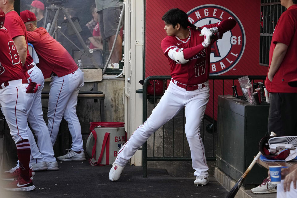 Los Angeles Angels' Shohei Ohtani warms up in the dugout at he waits to bat during the first inning of a baseball game Tuesday, Aug. 22, 2023, in Anaheim, Calif. (AP Photo/Mark J. Terrill)