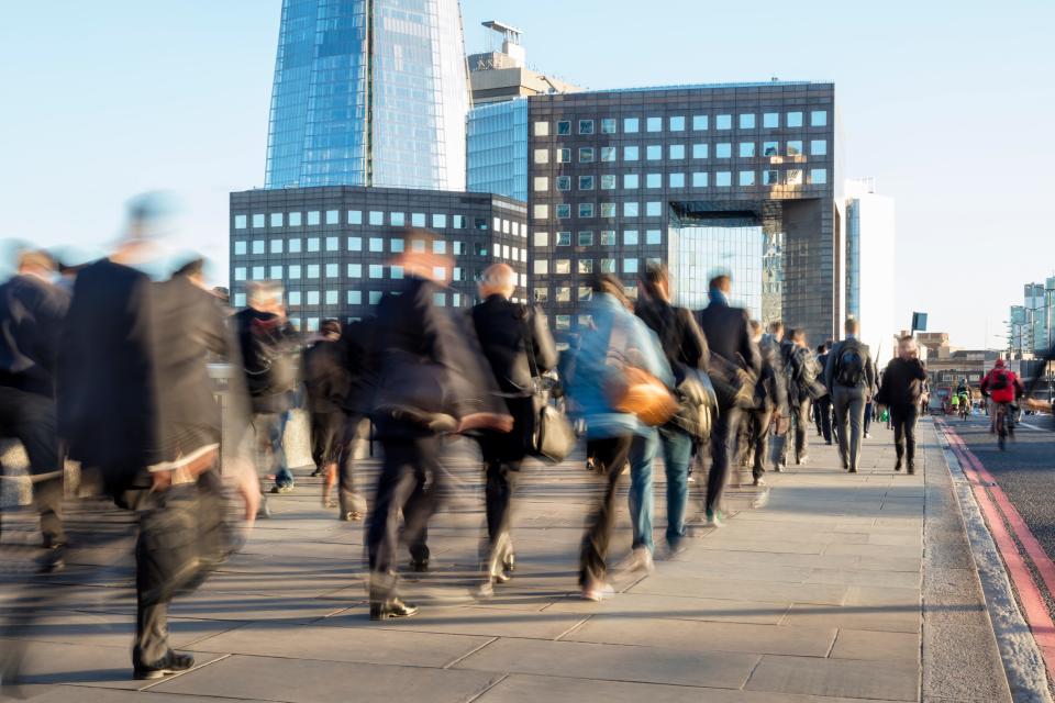 Blurred image of business commuters crossing London Bridge, office buildings with The Shard are visible in the background, London, England