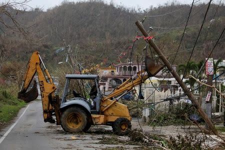 FILE PHOTO: A worker uses a backhoe loader to remove damaged electrical installations from a street after the area was hit by Hurricane Maria in Yabucoa, Puerto Rico on September 22, 2017. REUTERS/Carlos Garcia Rawlins/File Photo