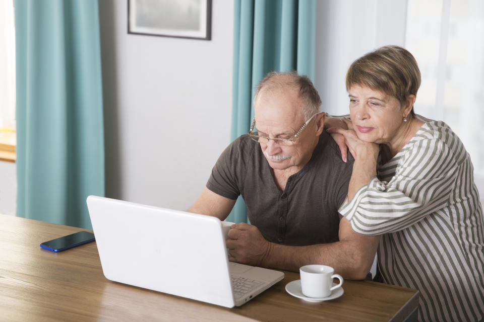 elderly man connecting to the Internet from home. healthy seniors lifestyle. work from home. Senior couple using a laptop, in a stylish living room,