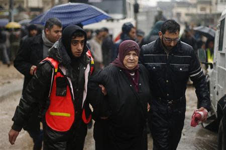 Members of Palestinian civil defense help a woman after she was evacuated from her house that was flooded with rainwater on a stormy day in the northern Gaza Strip December 14, 2013. REUTERS/Suhaib Salem