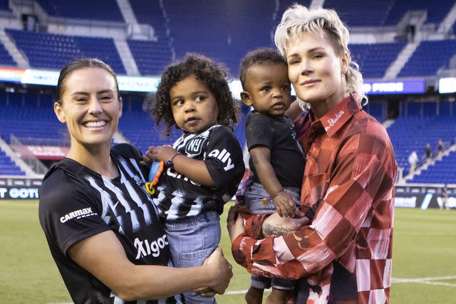 <p>Ira L. Black - Corbis/Getty</p> Ali Krieger and Ashlyn Harris hold their son and daughter in May 2023