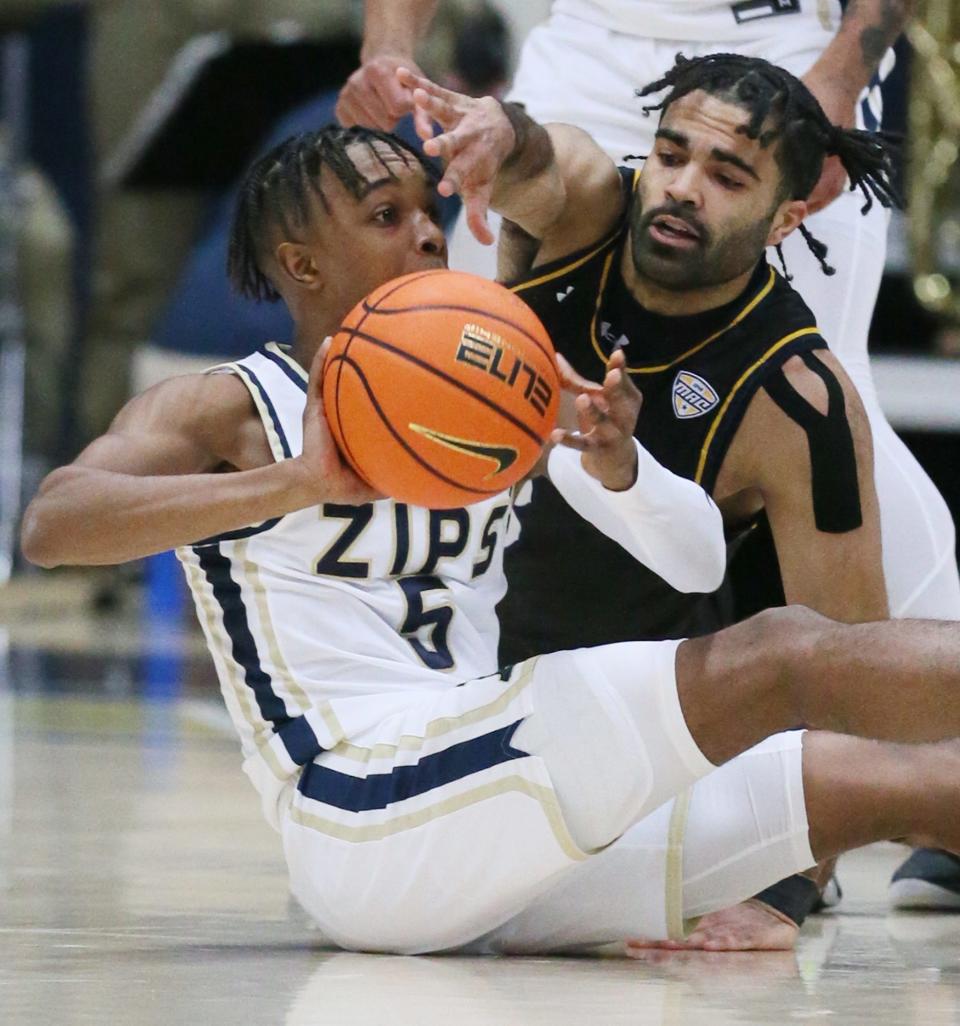 University of Akron's Tavari Johnson looks to pass from the floor as Kent State University's Sincere Carry defends during their MAC conference game at James  A. Rhodes Arena in Akron on Friday.