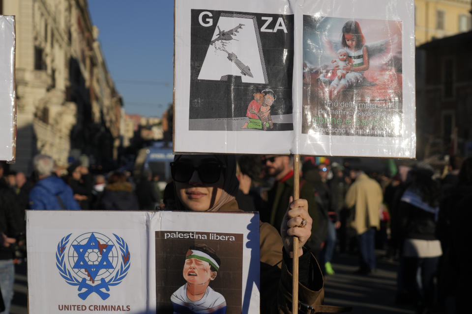 A woman holds placards, reading, bottom right: "Free Palestine, and top right: More than half of the martyrs in Gaza are women and children. Where are the human rights", during a rally in support of the Palestinians in Rome, Saturday, Jan. 13, 2024. (AP Photo/Gregorio Borgia)