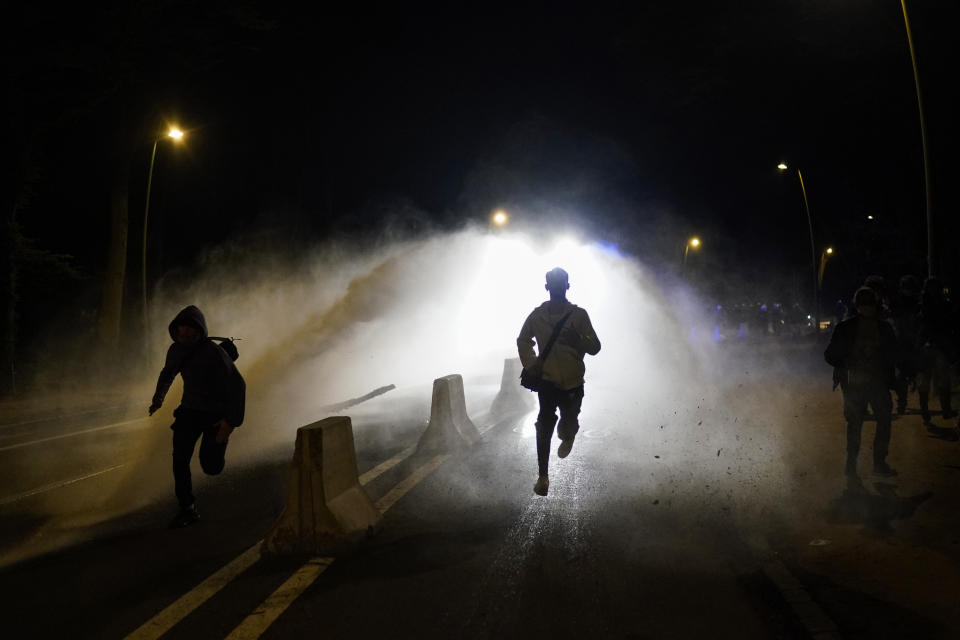 FILE - In this Thursday, April 1, 2021 file photo, police use a water cannon during clashes at the Bois de la Cambre park in Brussels. Brussels prosecutors warned potential party-goers they should stay away from an illegal gathering planned this weekend in one of the city's biggest park as police briefly detained one of the organizers on Tuesday, April 27, 2021. (AP Photo/Francisco Seco, File)