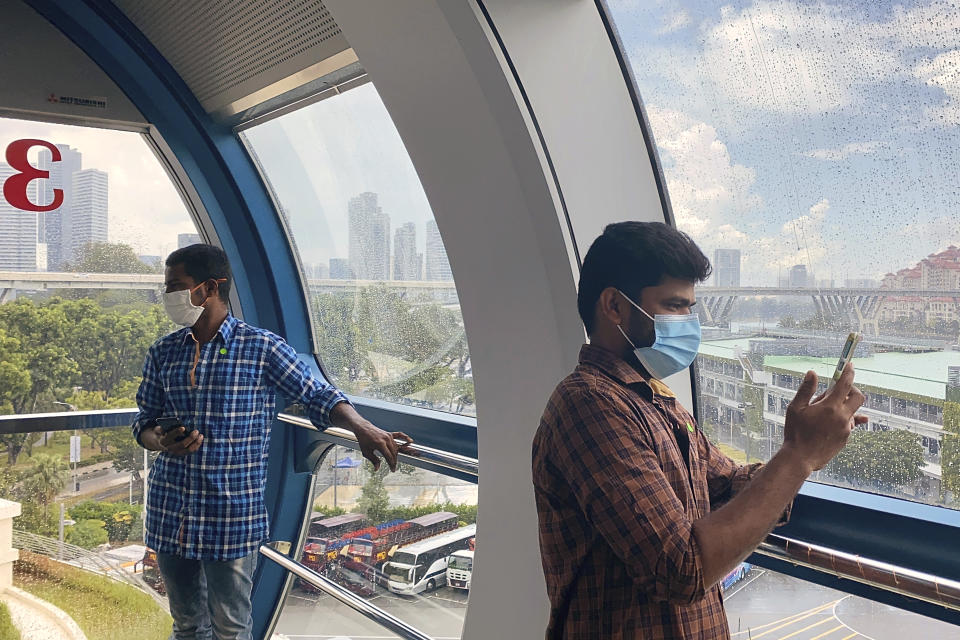 Migrant worker Natarajan Pandiarajan, right, enjoys the view on board the Singapore Flyer attraction in Singapore on March 7, 2021. He is among at least 20,000 migrant workers who will be treated to rides by members of the public and businesses. Migrant workers are getting a bird's eye view of Singapore, with the public's help. (AP Photo/Annabelle Liang)