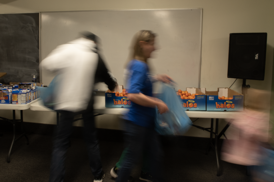 Volunteers are quick to unpack different boxes of food for an assembly line to fill bags at Portage Community Chapel in Ravenna.