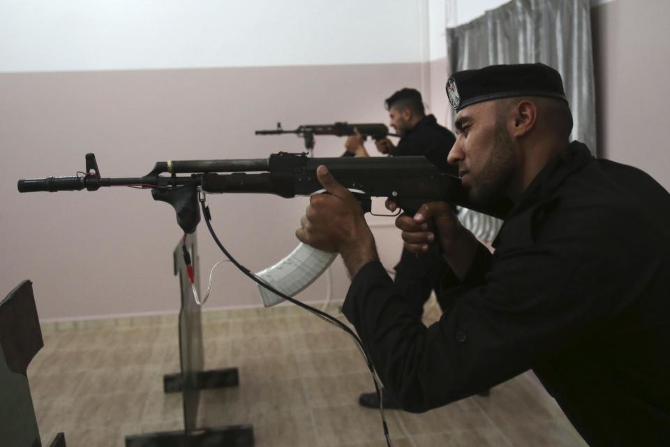 Palestinian security officers Ahed Abu Shabban, 23, foreground, and Muhmmad Debo, 22, aim electronically-modified AK-47 rifles at the headquarters of the security training department of the Hamas interior ministry in Gaza City, in the northern Gaza Strip on Thursday, April 10, 2014. The laser-fitted rifles are a money saver that eliminates the need to train with live ammunition, which is in short supply in Gaza. (AP Photo/Adel Hana)