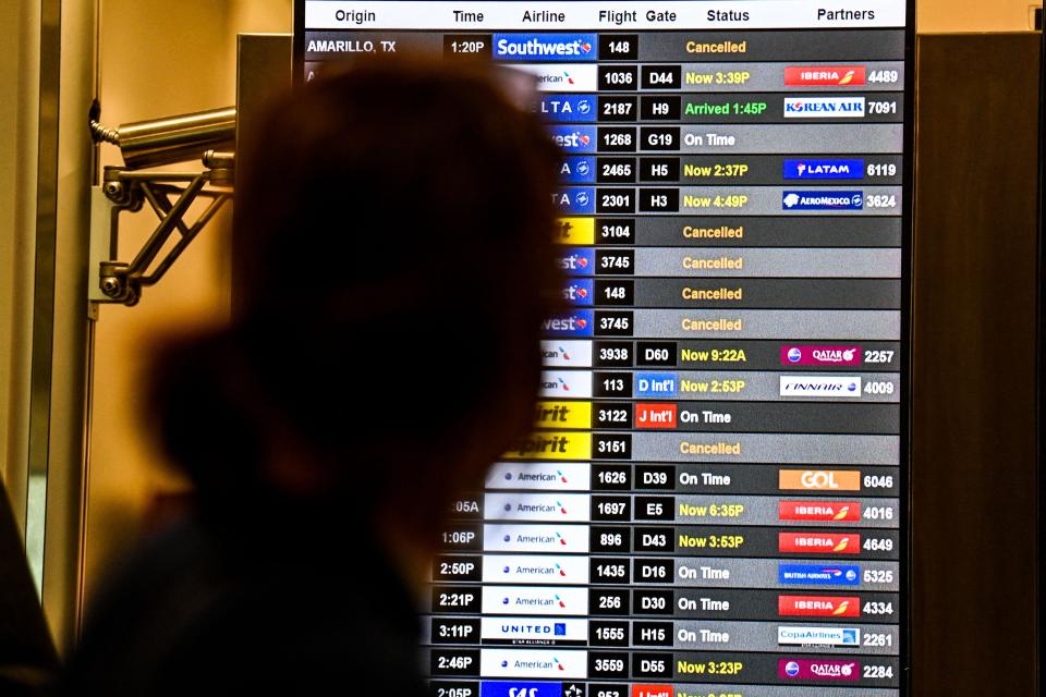 People check flight information at Miami International Airport as thousands of flights were canceled across the U.S. on January 3, 2022.