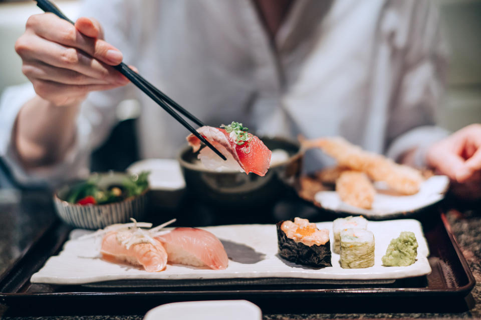 A woman eating sushi with chopsticks.