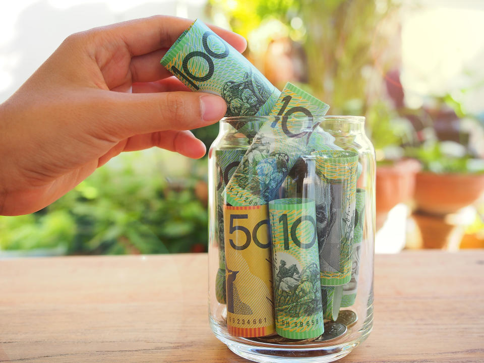 Close-Up Of Hand Inserting Paper Currency In Bottle