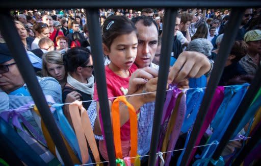 People attach colourful ribbons with the names of Jewish children on the fence of a former Jewish orphanage during ceremonies in Warsaw marking the 70th anniversary of the start of Nazi Germany's mass deportation of Jews from the Warsaw Ghetto to the death camp of Treblinka