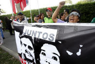 A woman shouts slogans against Peru's former President Alan Garcia outside the residence of Uruguay's ambassador to Peru, behind a sign showing an image of Garcia and Keiko Fujimori in Lima, Peru, Sunday, Nov. 18, 2018. Garcia has sought asylum in Uruguay's diplomatic mission hours after a judge retained his passport as part of a corruption probe, Peru's foreign ministry announced Sunday. (AP Photo/Karel Navarro)