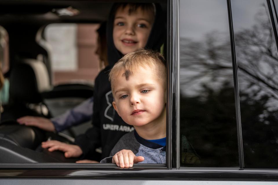 Two young boys look out the window after being blessed during a drive-through service on Ash Wednesday at the Christ Episcopal Church in Ridgewood in 2023.