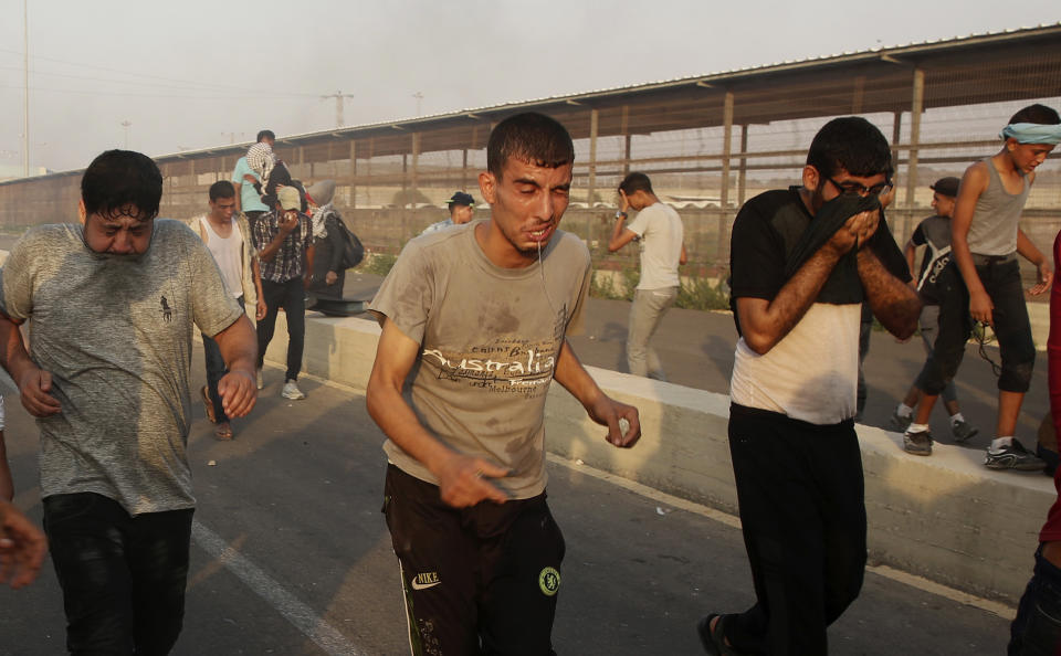 Protesters run to cover from teargas fired by Israeli soldiers during a protest at the entrance of Erez border crossing between Gaza and Israel, in the northern Gaza Strip, Tuesday, Sept. 4, 2018. The Health Ministry in Gaza says several Palestinians were wounded by Israeli fire as they protested near the territory's main personnel crossing with Israel. (AP Photo/Adel Hana)