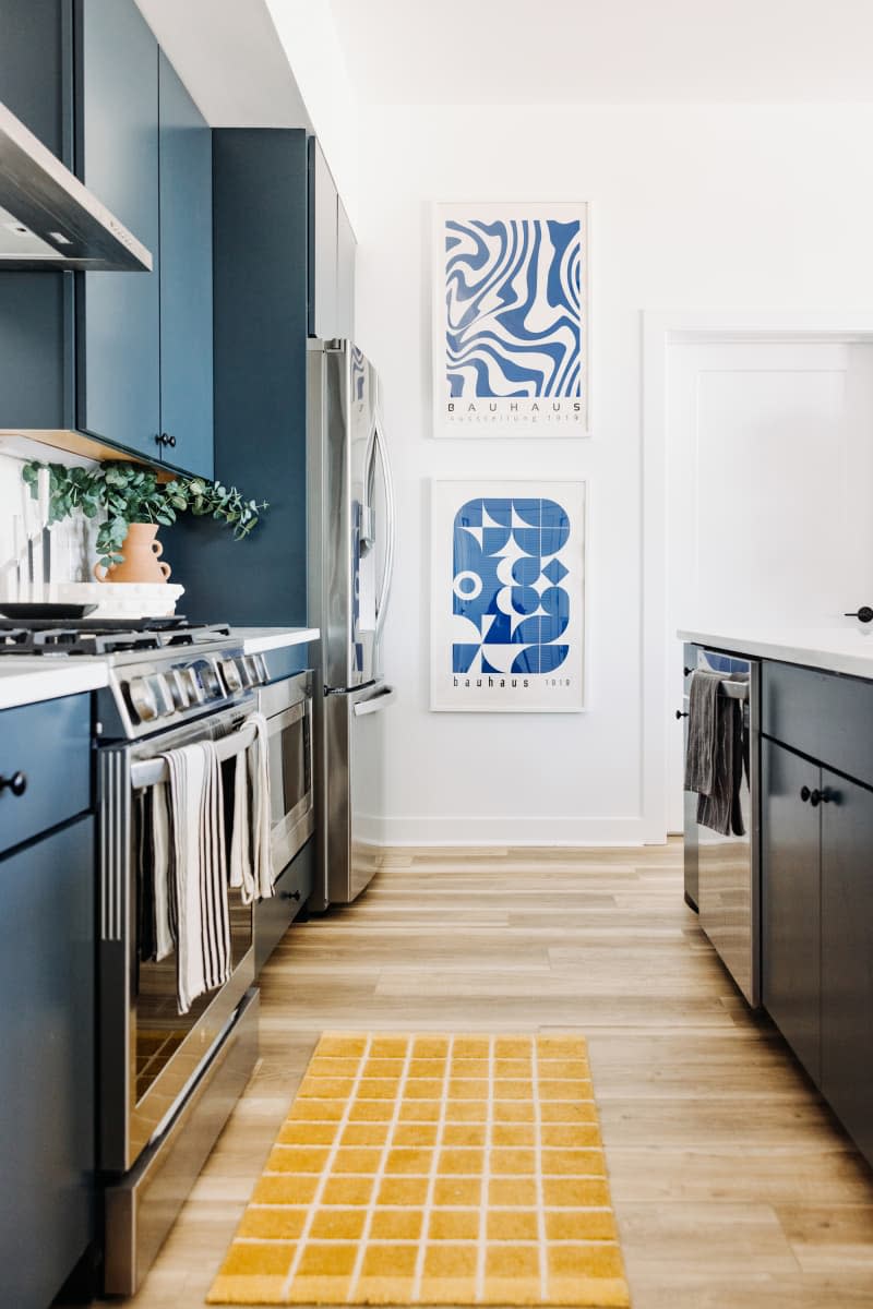 White kitchen with blue cabinets and blue and white art