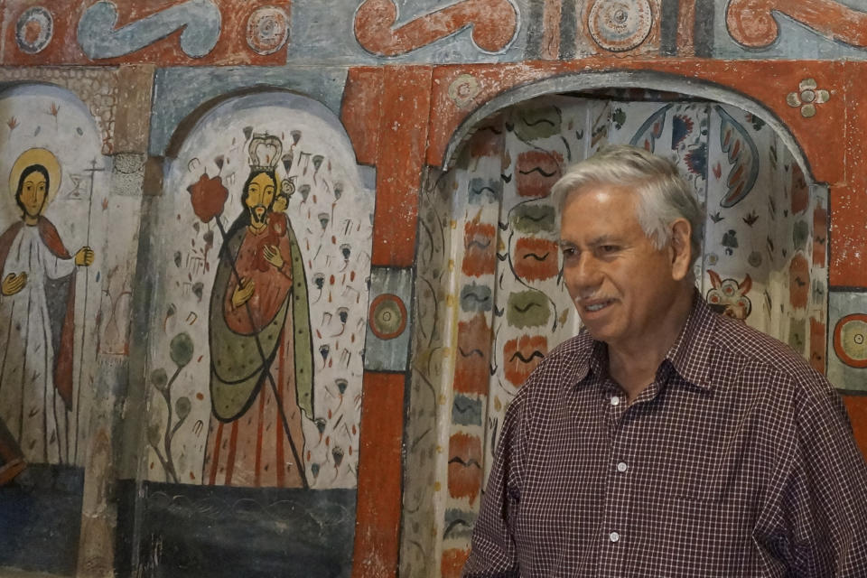 Master santero Felix Lopez – an artist trained in New Mexico's centuries-old tradition of religious sculpture and painting – stands in front of the 1810s reredo or altarpiece he cleaned and preserved in the Holy Rosary Mission Church in Truchas, New Mexico, Sunday, April 16, 2023. To his right is a painting of St. Joseph, a popular saint in these remote villages that have kept the Catholic faith first brought by Spanish missionaries in the 17th century and now fight to preserve the churches as population, and congregations, dwindle. (AP Photo/Giovanna Dell'Orto)