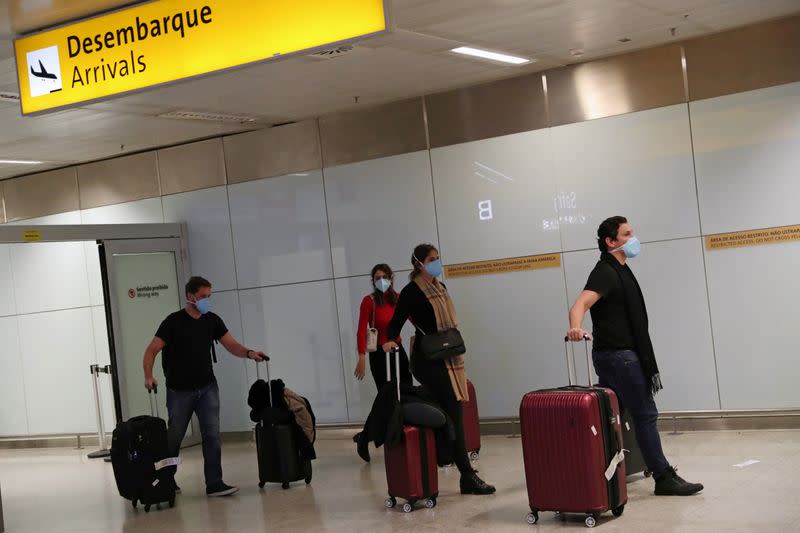 Travellers wearing protective face masks as a precautionary measure arrive on a flight from Italy, after the second case of coronavirus in Sao Paulo was confirmed, at Guarulhos International Airport in Guarulhos