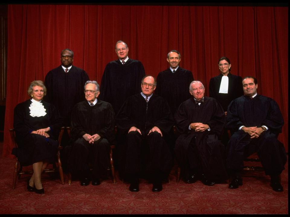 Supreme Court Justices Scalia, Ginsburg, Stevens, Souter, Chief Rehnquist, Kennedy, Blackmun, Thomas & O'Connor sitting for portrait.