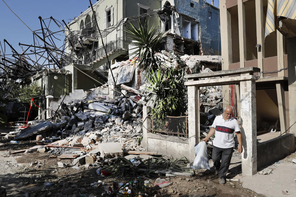 A Lebanese man carries his belongings as he leaves his destroyed house near the scene where an explosion hit on Tuesday the seaport of Beirut, Lebanon, Thursday, Aug. 6, 2020. Lebanese army bulldozers plowed through wreckage to reopen roads around Beirut's demolished port on Thursday as the government pledged to investigate the devastating explosion and placed port officials under house arrest. (AP Photo/Hussein Malla)