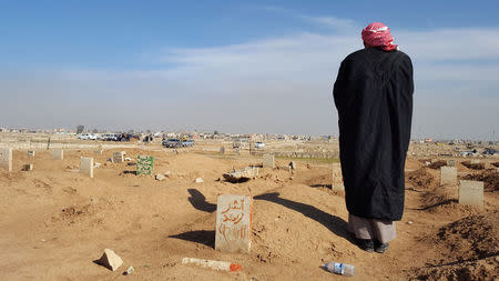 The father of Atheer Ali stands beside his grave in Gogjali cemetery in eastern Mosul, Iraq, February 4, 2017. Picture taken February 4, 2017. REUTERS/Stephen Kalin