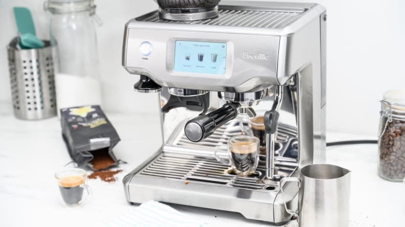 The Breville Barista Touch on a white countertop with surrounding accessories.