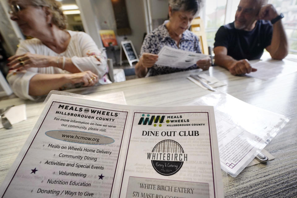 Senior citizens, having breakfast as part of the Meals on Wheels "Dine Out Club", look over the special menu at the White Birch Cafe, Wednesday, Aug. 16, 2023, in Goffstown, N.H. The special menu lists the calories, carbohydrates and sodium content for the meals, which have to meet a dietician-approved one-third of the USDA recommended daily requirements for adults under the federal Older Americans Act Nutrition Program. (AP Photo/Charles Krupa)