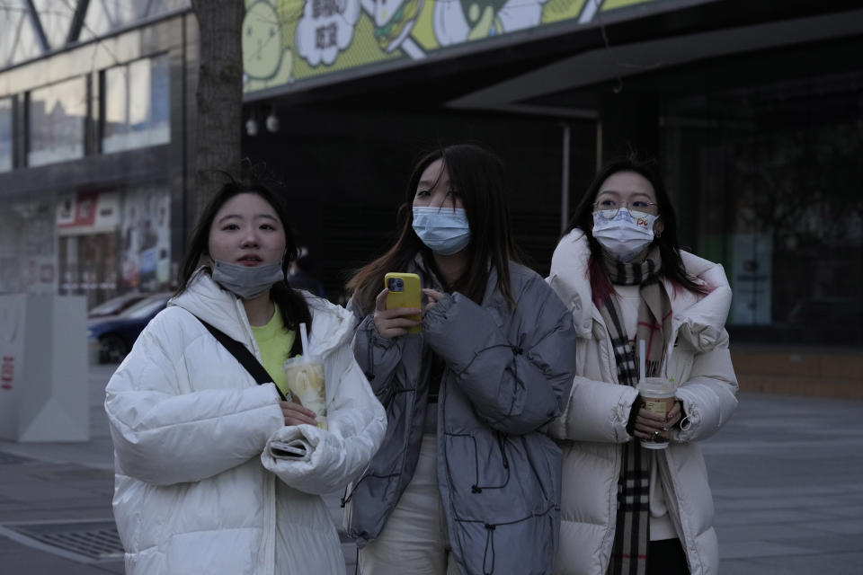 Shoppers walk along a mall district in Beijing, Thursday, Dec. 29, 2022. China is on a bumpy road back to normal life as schools, shopping malls and restaurants fill up again following the abrupt end of some of the world's most severe restrictions even as hospitals are swamped with feverish, wheezing COVID-19 patients. (AP Photo/Ng Han Guan)