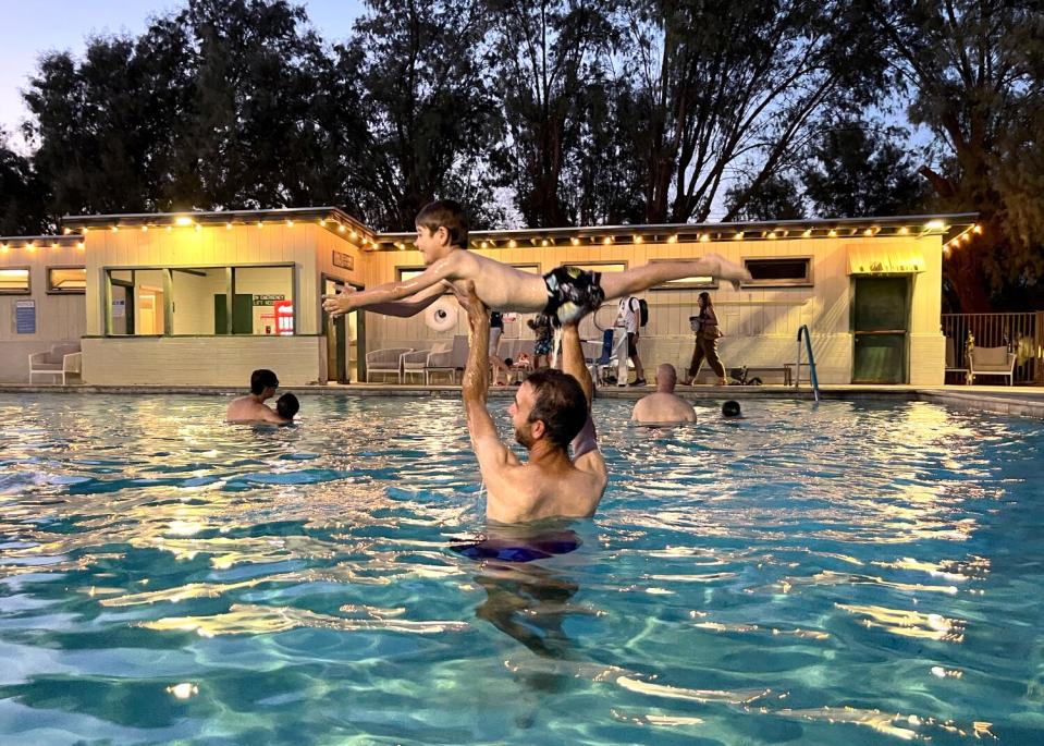 Nicolas Combaret holds up his son, Paulin Combaret, while they play in the pool at The Ranch at Death Valley.