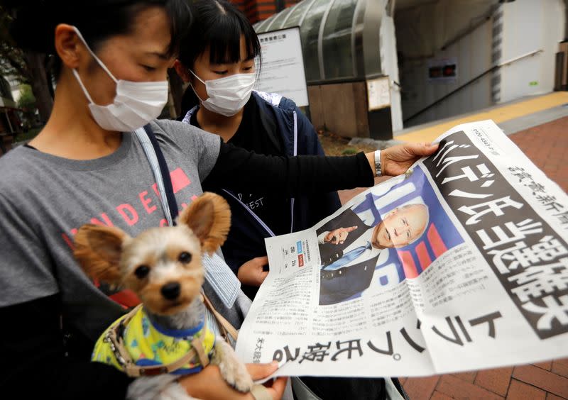 People reads an extra edition of a newspaper reporting that Democratic U.S. presidential nominee Joe Biden is projected to win the 2020 U.S. presidential election, in Tokyo