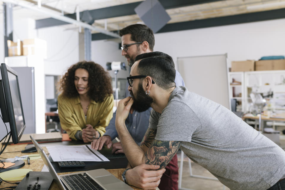 Small group of co-workers working together in a startup business office space.