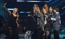 JoJo Siwa, left, takes a selfie with BTS on stage as they accept the award for favorite pop duo or group at the American Music Awards on Sunday, Nov. 21, 2021 at Microsoft Theater in Los Angeles. (AP Photo/Chris Pizzello)